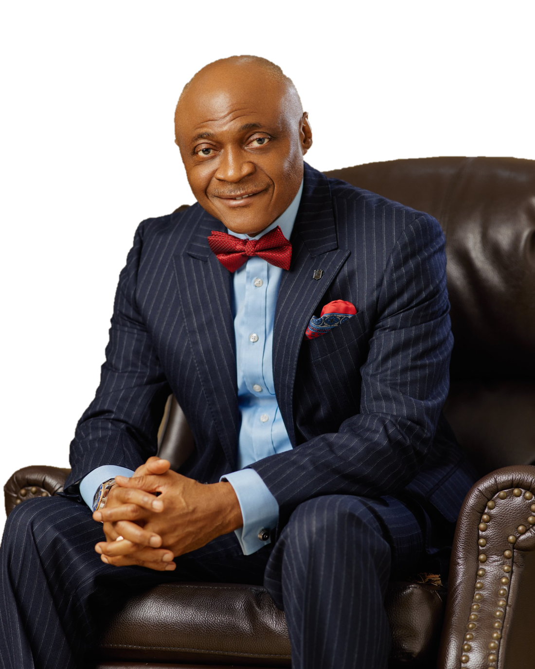 Dr Ken Onyeali Ikpe, seated in a leather armchair, in a navy pinstripe suit and red bow tie